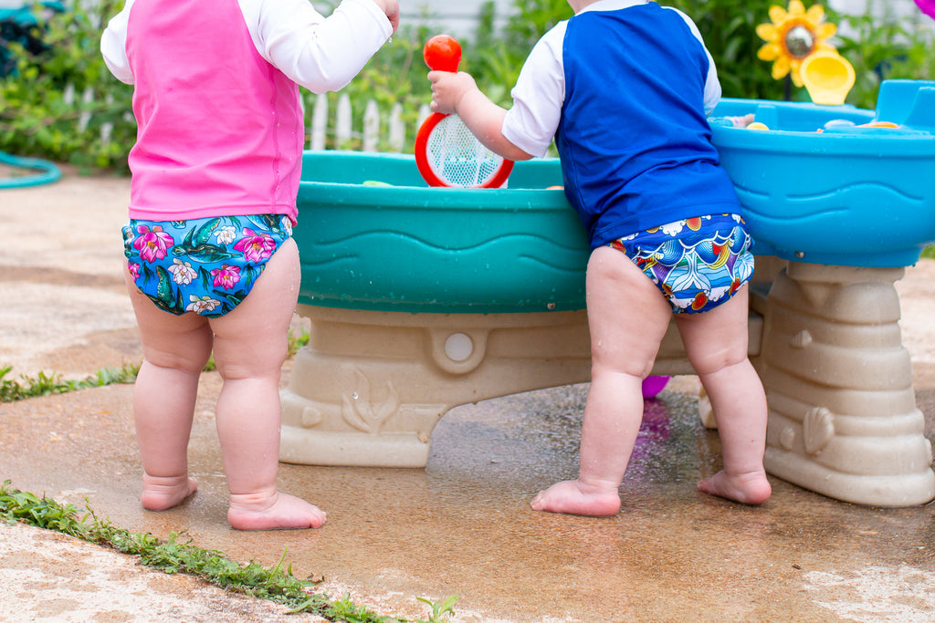 babies wearing reusable swim diapers playing in a water table