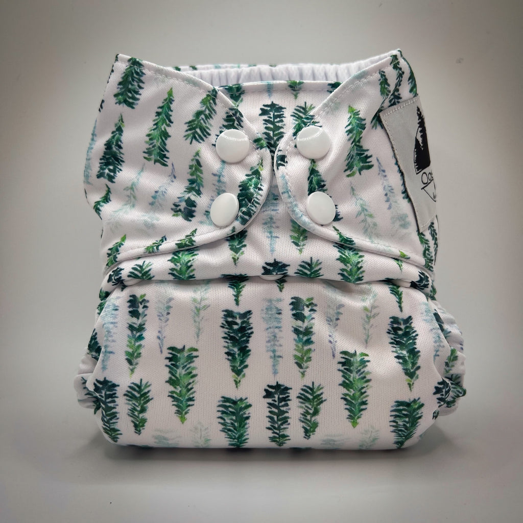 A cloth pocket diaper with a pine tree print and athletic wicking jersey interior.