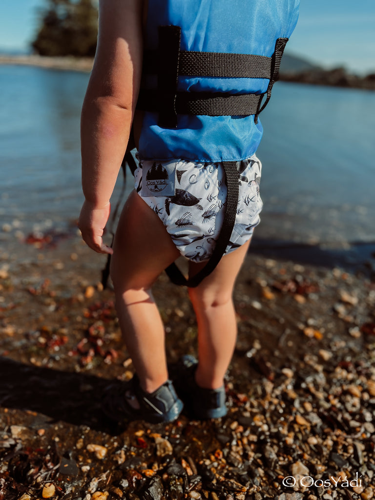 baby playin by the water in a reusable swim diaper